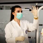 researcher holding up a microscope slide and looking at it